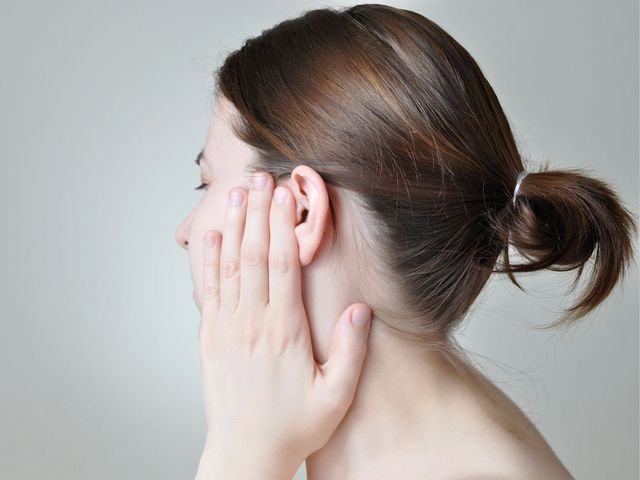 A woman holding her hand to a blocked ear