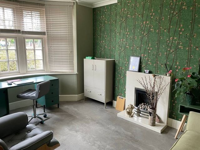 The clinic room at Happy Ears in Woodthorpe, with a desk by the window and a fireplace