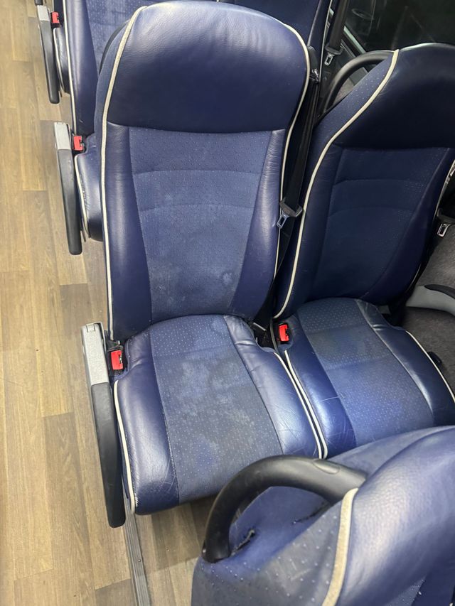 Blue padded seats on a bus or coach, seen from the aisle.