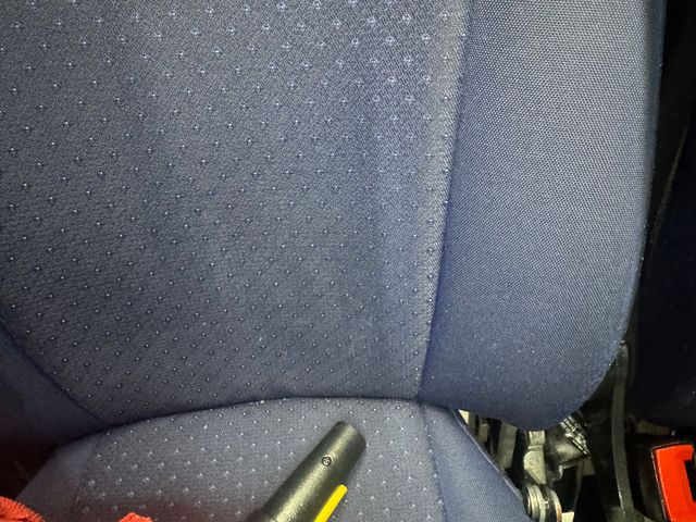 Blue car seat with a black handheld device resting near the bottom edge