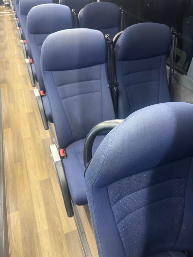 Blue seats inside a train or bus aisle with wood-pattern flooring