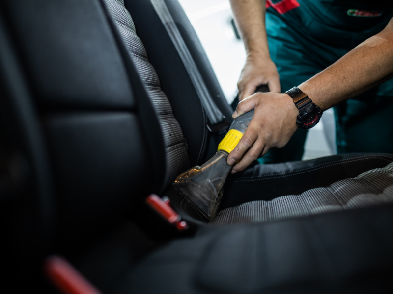 Person buckling a yellow car seat belt in a vehicle seat