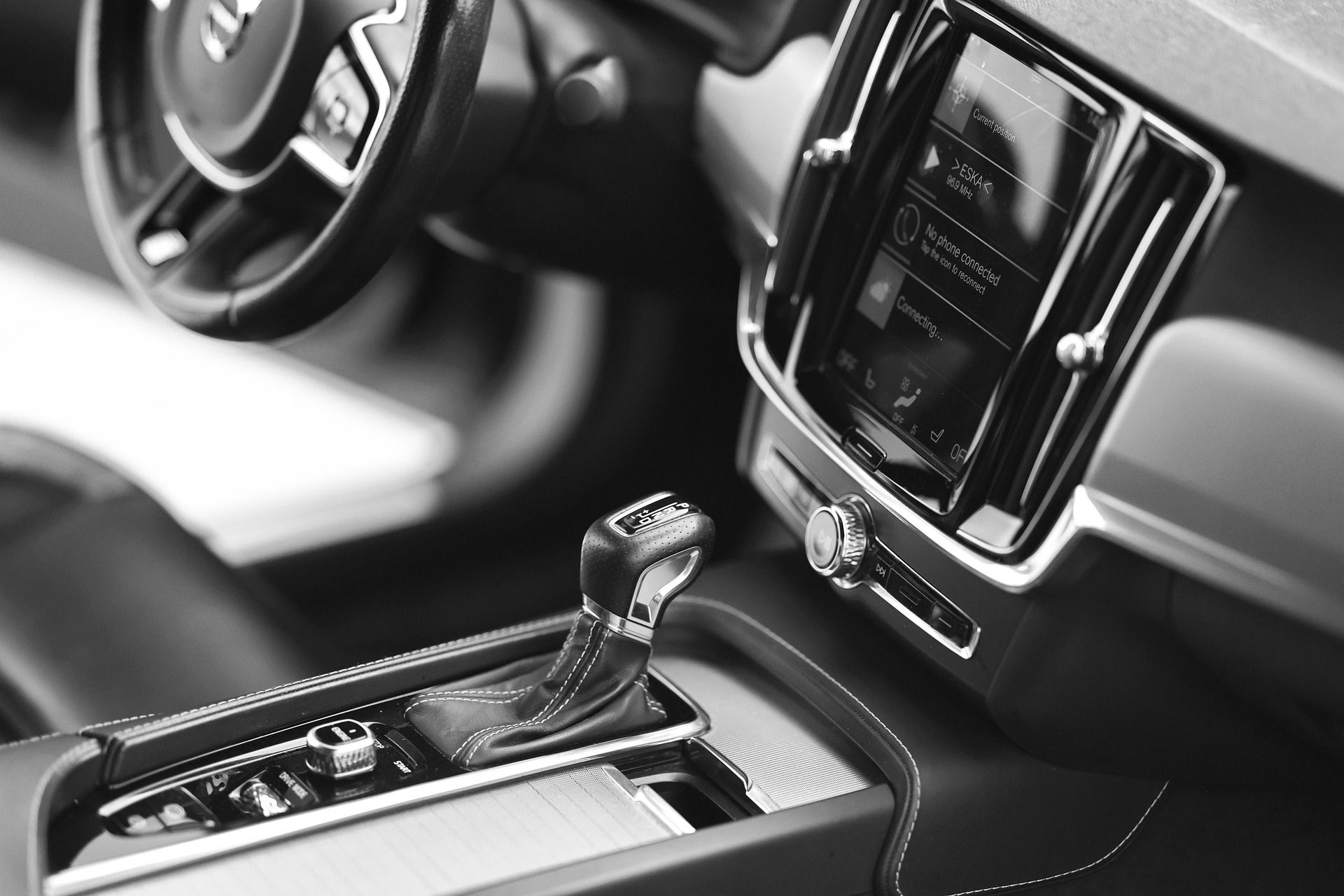 Car interior with steering wheel, dashboard display, and center console gear shifter.