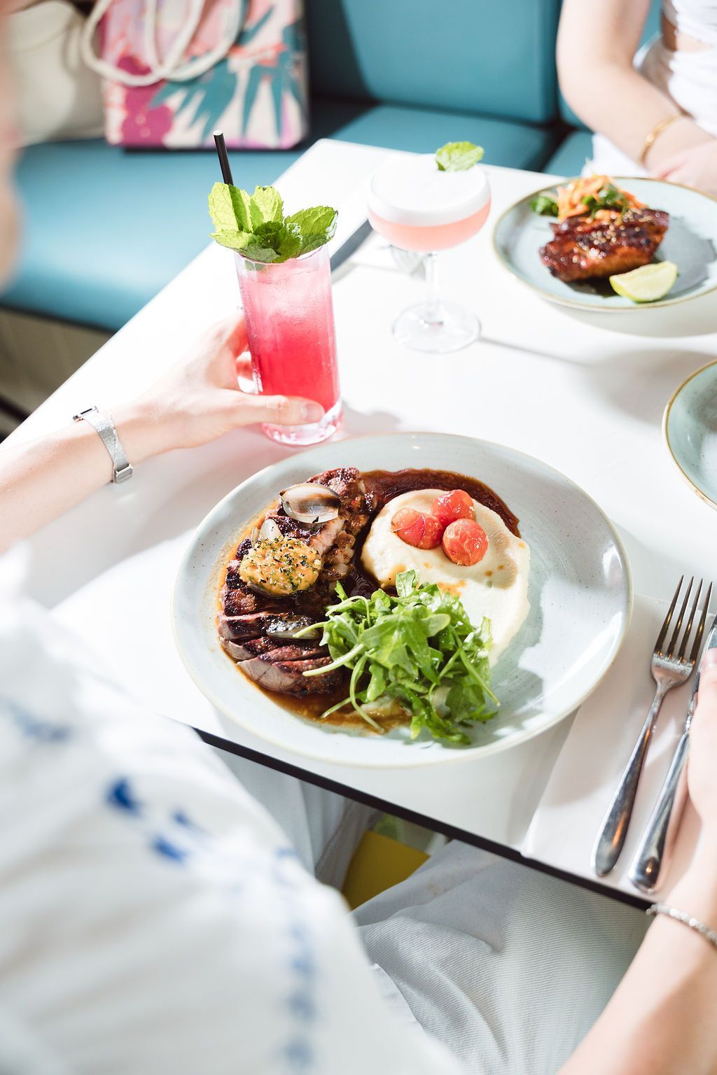Grilled seafood platter with multiple bowls and drinks on a table with a blue tablecloth.