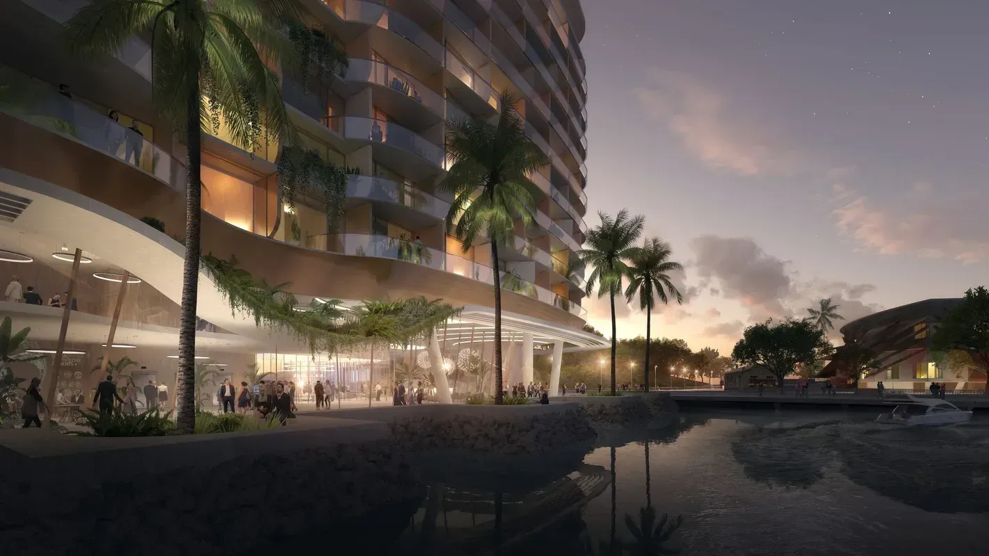 Evening view of waterfront building with palm trees and water reflecting lights.