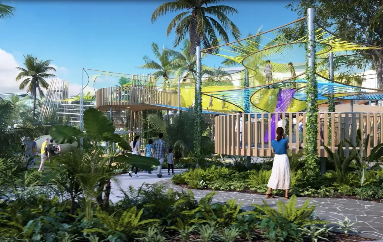 A park scene with people walking, lush greenery, play structures, and a wooden fence.