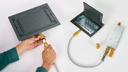 A person is plugging a cable into a box.