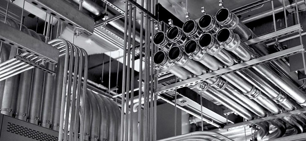 A black and white photo of a bunch of pipes hanging from the ceiling of a building.