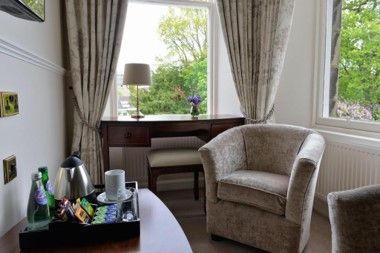 Cozy hotel room with armchair, desk, lamp, and large window with green view