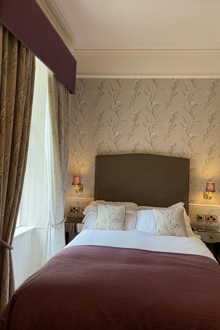 Cozy bedroom with a bed, brown headboard, white pillows, and purple curtains by a window
