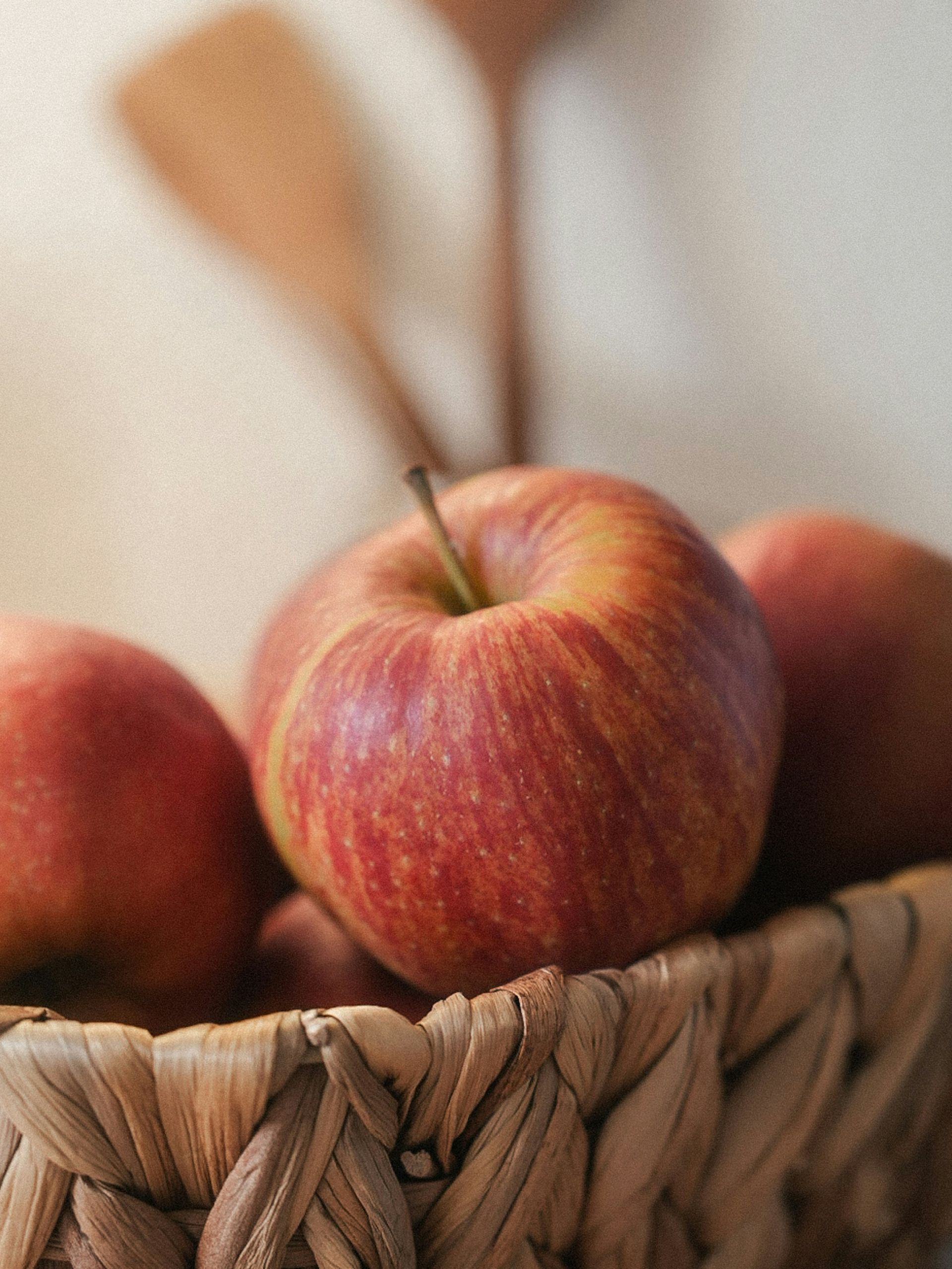 Basket of red apples with a blurred apple in the background