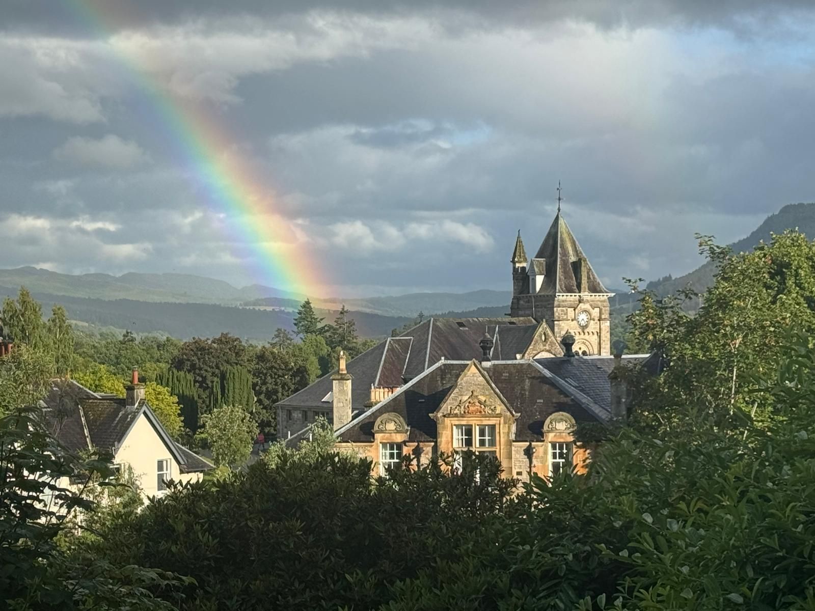 Rainbow over a village with stone houses and a church under cloudy skies