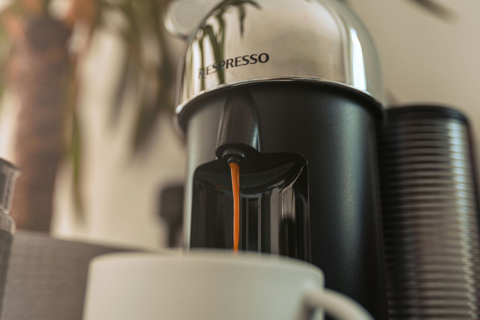 Coffee machine pouring espresso into a cup, with stacked black cups beside it