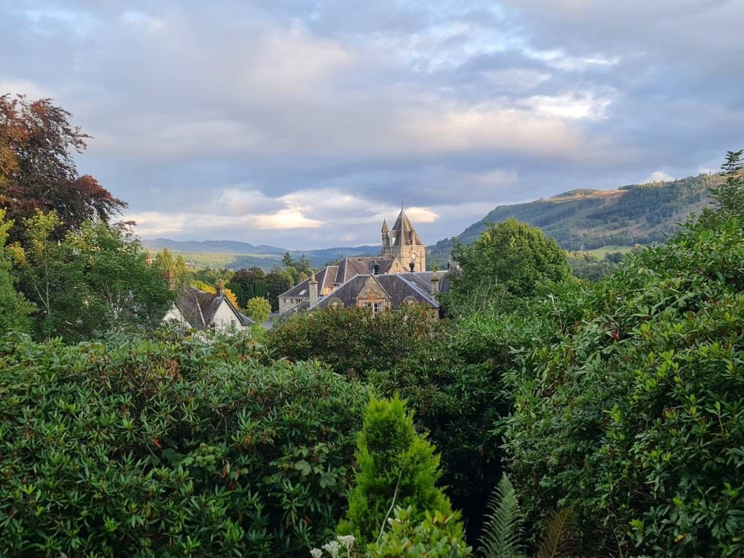Village church and rooftops among green hills under a cloudy sky in pitlochry perthshire scotland hotel with a view