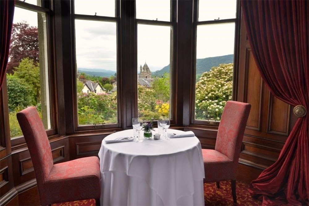 Elegant dining nook with round table, two chairs, bay window, and garden view