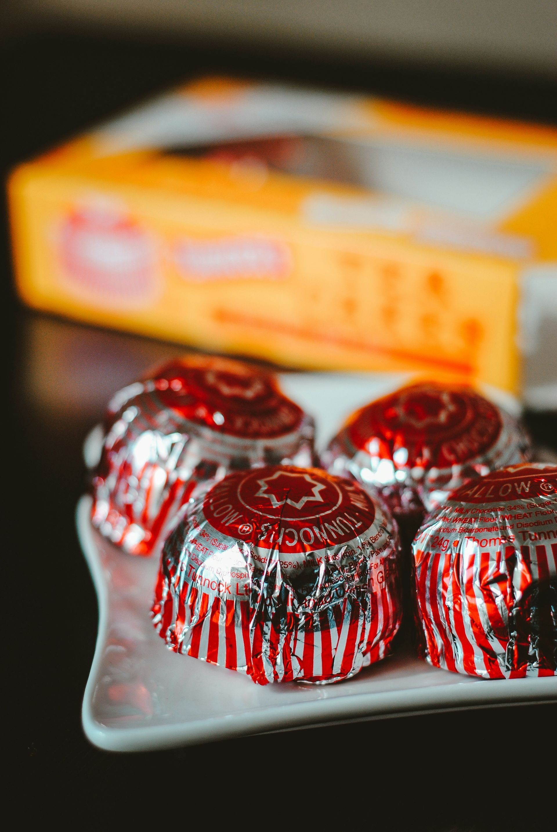 Red and silver-wrapped chocolates arranged on a tray with an orange box in the background