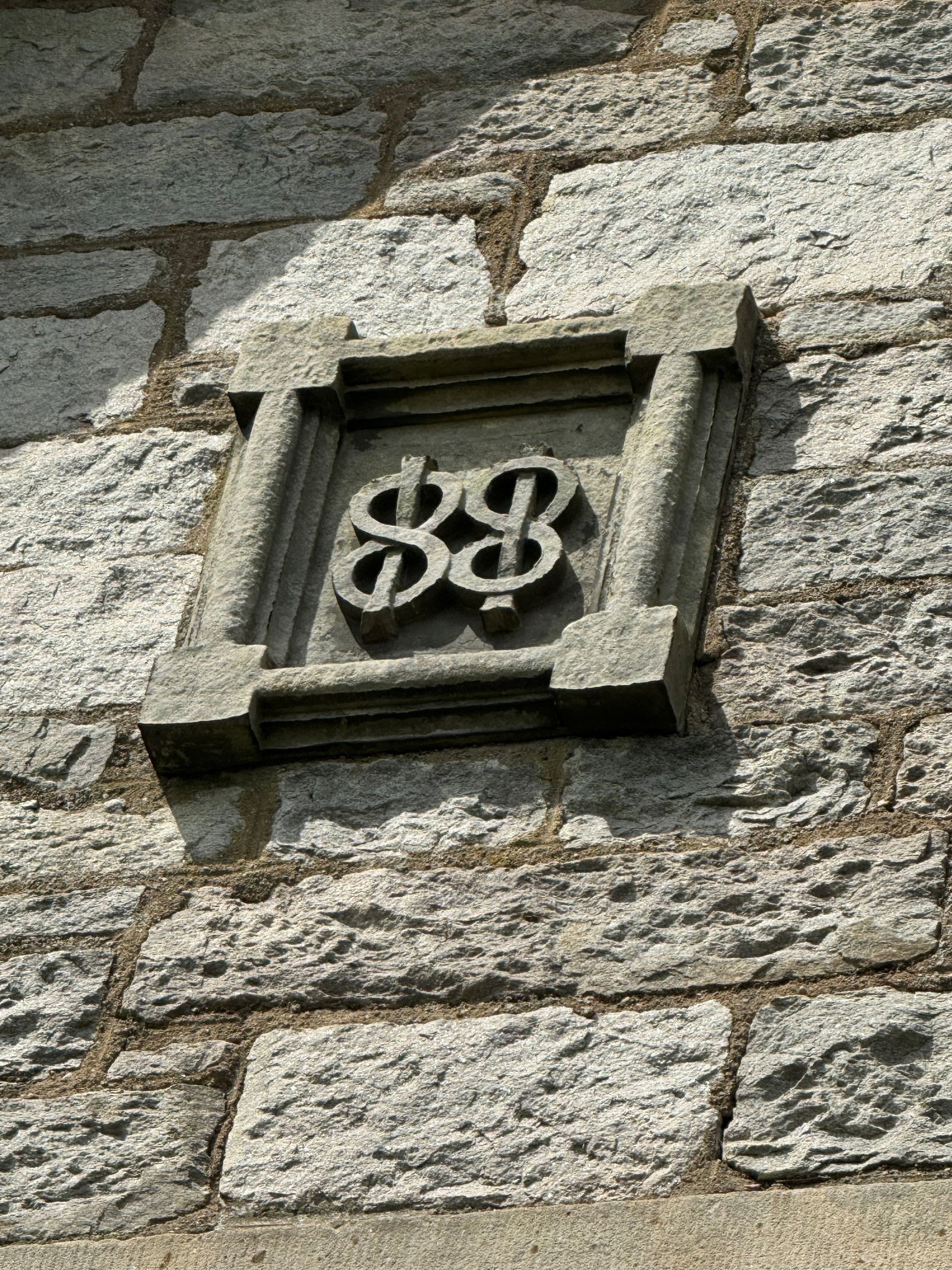 Stone wall with a small carved decorative emblem in a square frame