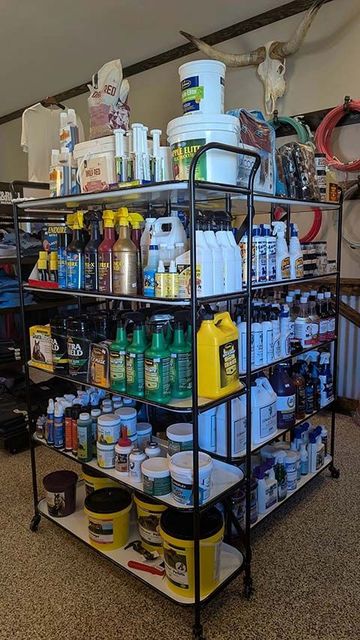 Kickin' Cowboy Spicy BBQ Sauce bottle with blue cap, surrounded by spice jars on a tiered display.