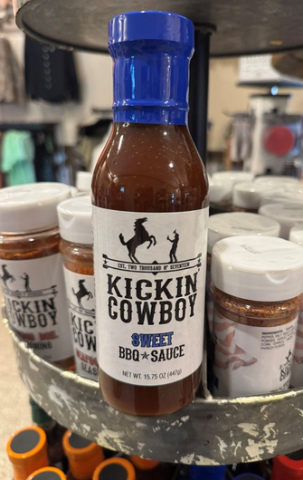 Kickin' Cowboy spicy BBQ sauce bottle with other spices on a tiered display.