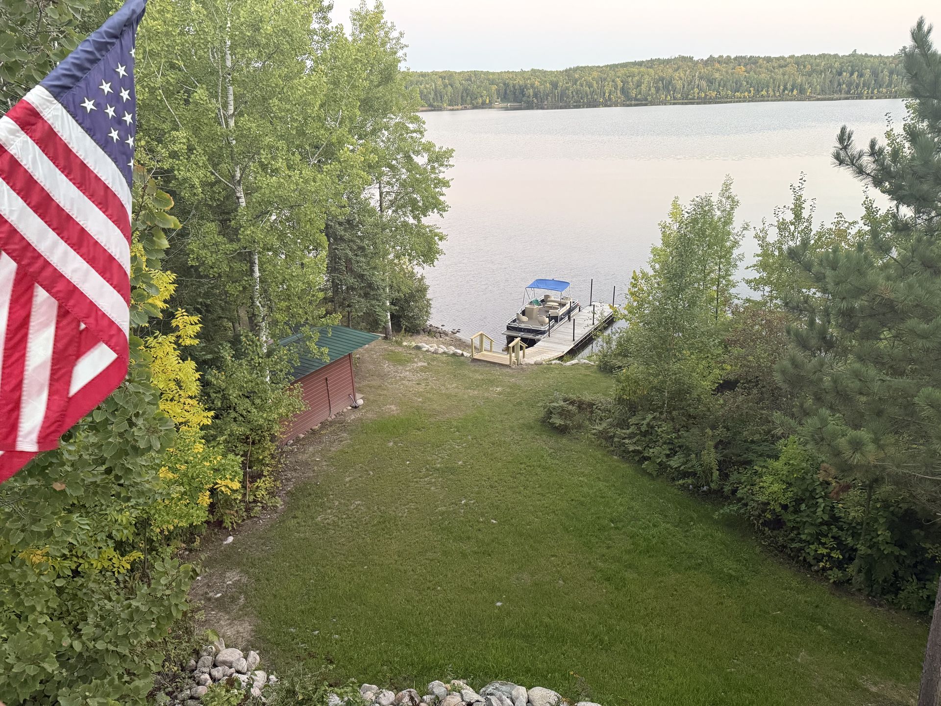 An american flag is flying on a balcony overlooking a lake.