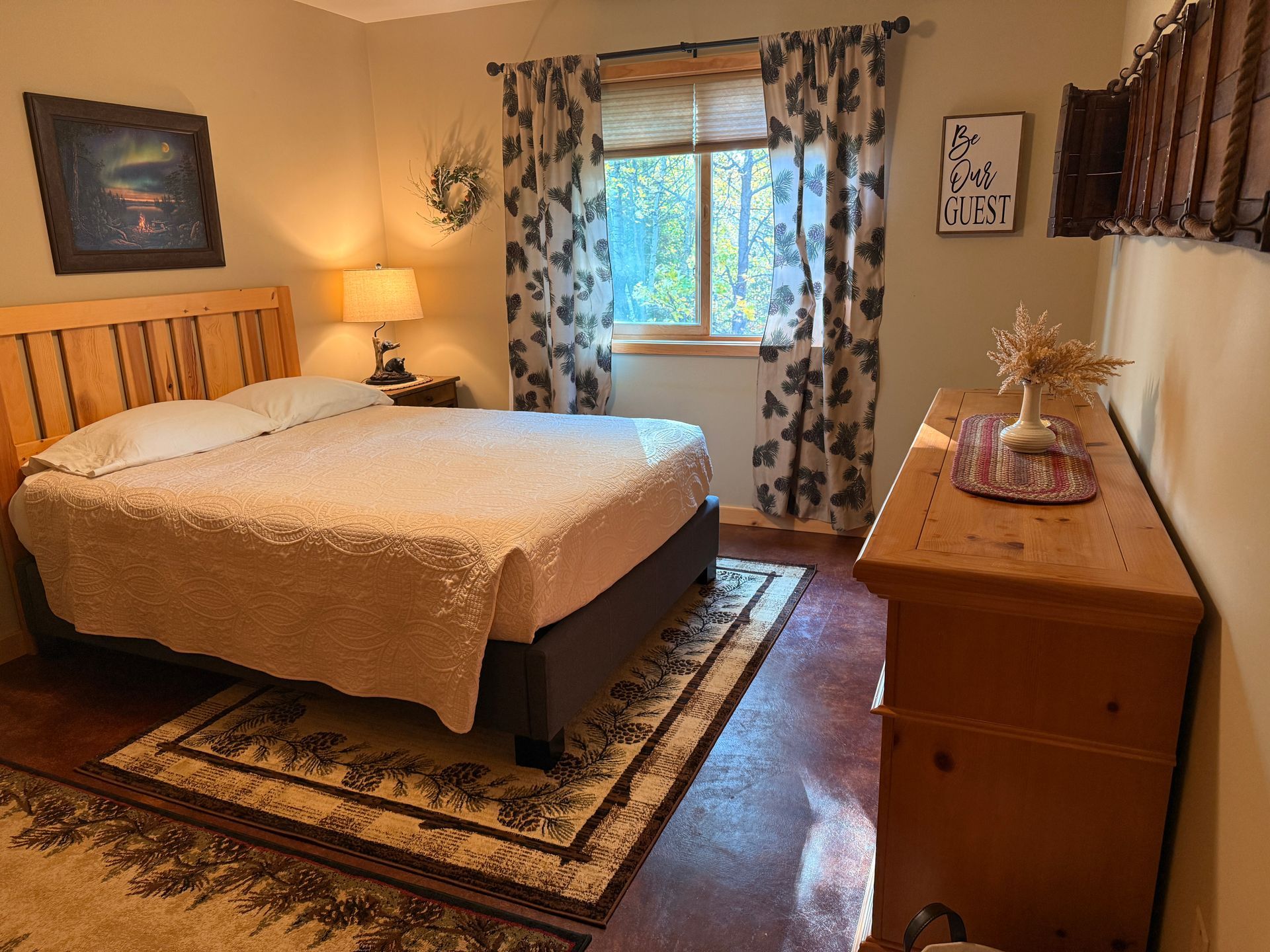 A bedroom with a bed , nightstand , lamp and painting on the wall.