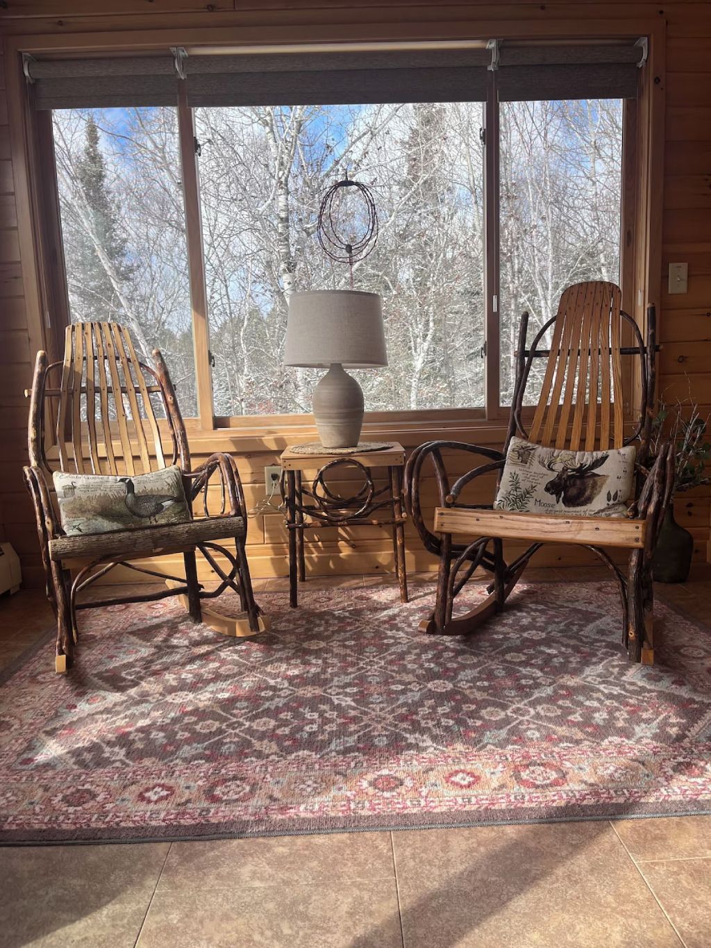 Two wooden rocking chairs are sitting in front of a large window in a living room.