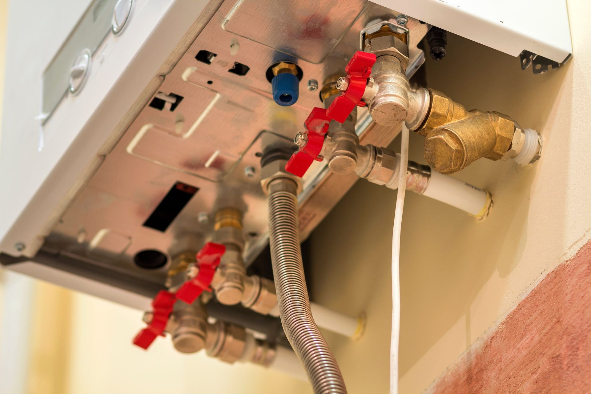 Under-sink plumbing valves and flexible hoses connected to a wall-mounted fixture