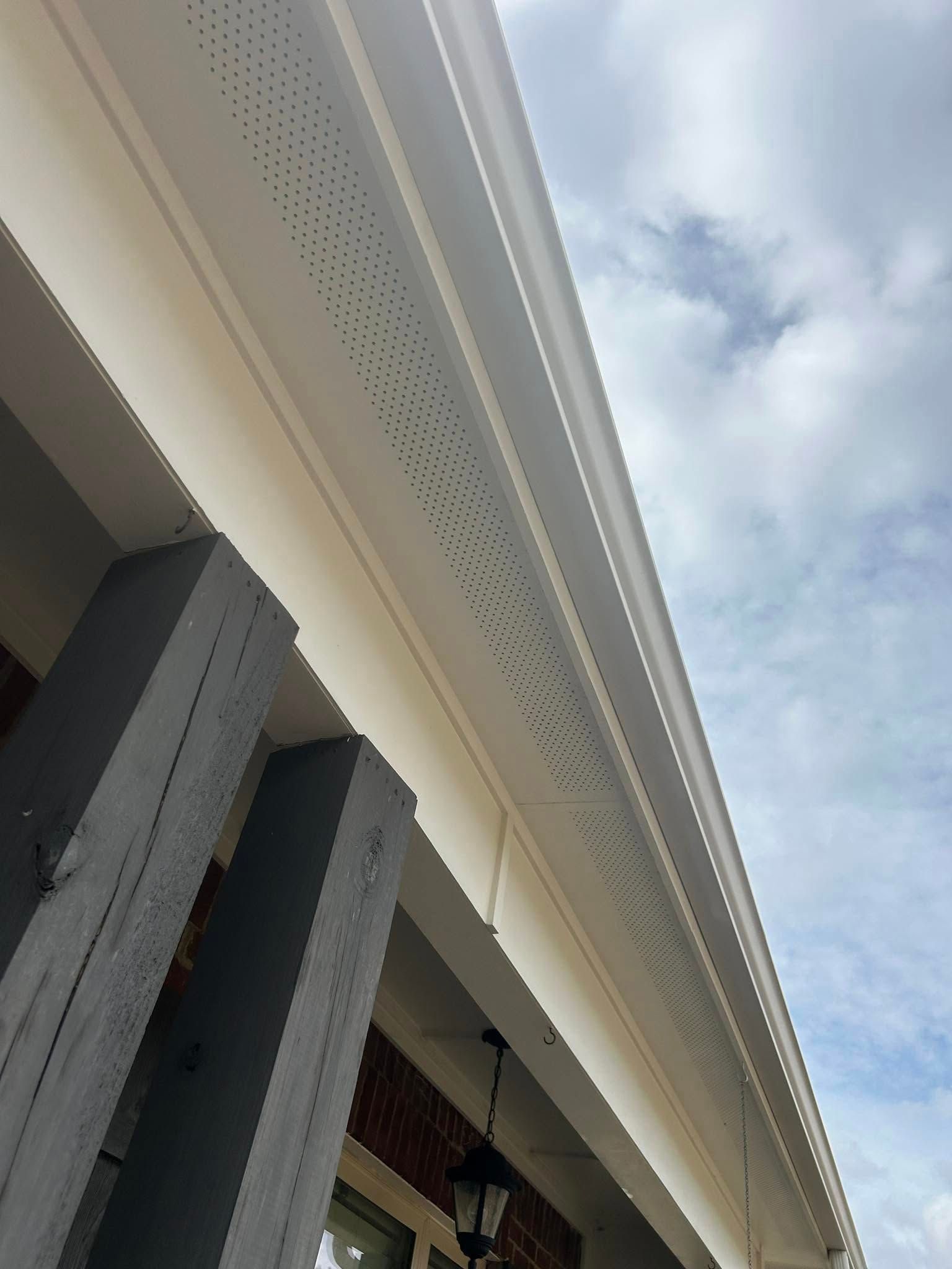 Upward view of a building’s eaves and columns against a cloudy sky
