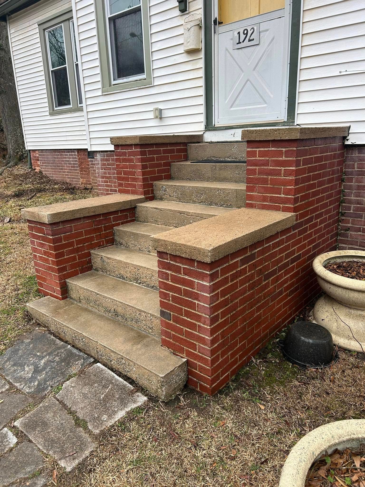 Brick front steps and porch with white siding and a light blue door at a house entrance