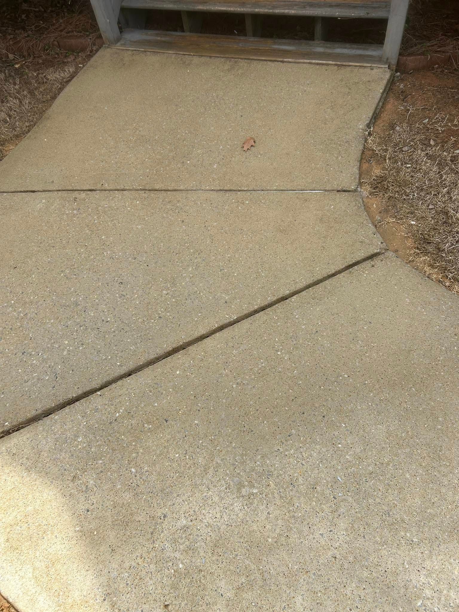 Concrete sidewalk path leading to steps, with a diagonal crack and gravel borders