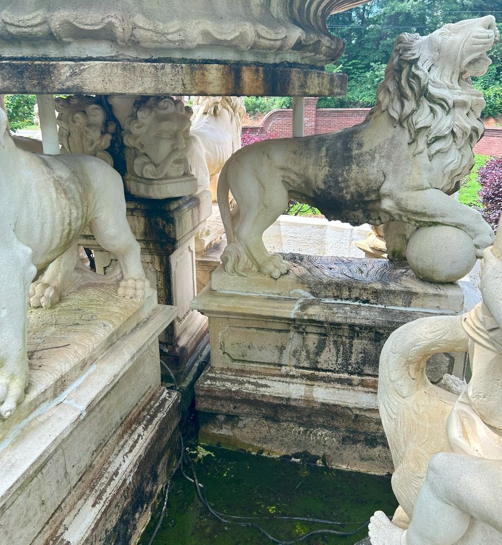 Stone lion statues around a small greenish fountain in a weathered courtyard
