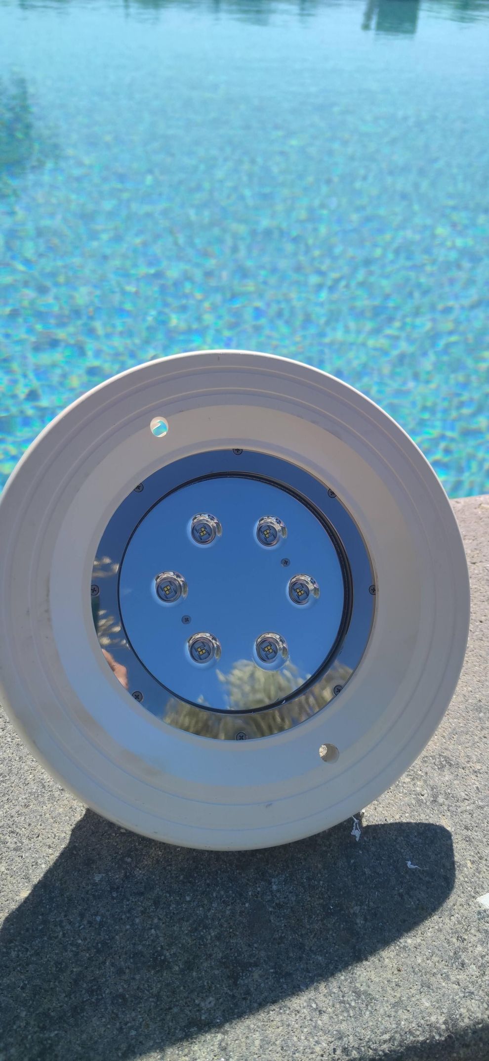 Bocchetta idromassaggio bianca per piscina, installata accanto all’acqua azzurra e limpida con riflessi del sole