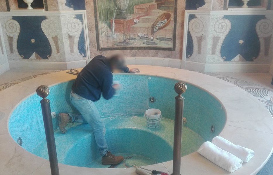 Persona china su una fontana o vasca interna piastrellata di turchese, circondata da mosaici decorativi e colonne.