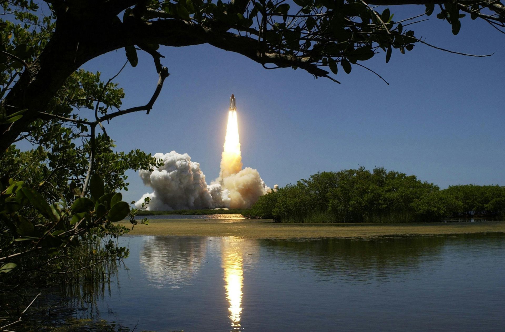 A rocket is taking off over a body of water