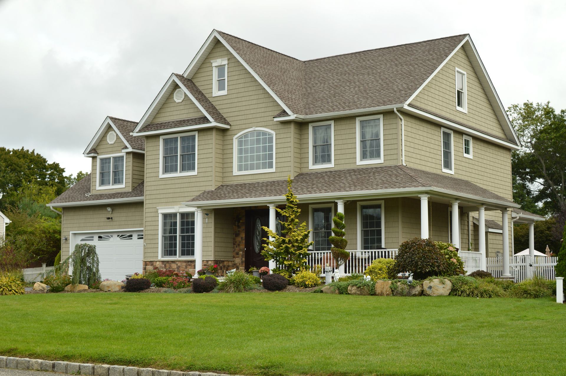 a beautiful beige house with brown singles and white trim