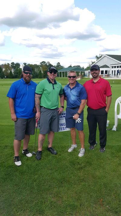 a group of men are posing for a picture on a golf course .