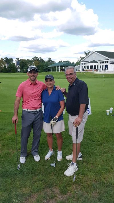 three people are posing for a picture on a golf course .