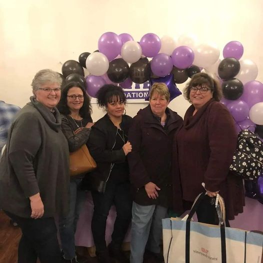 a group of women are posing for a picture in front of balloons .