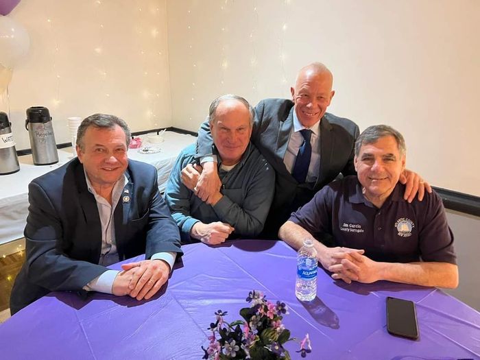 a group of men are sitting around a purple table