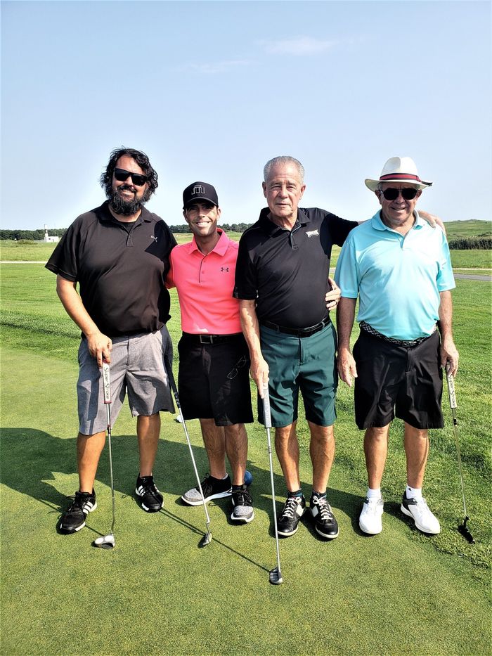 four men are posing for a picture on a golf course