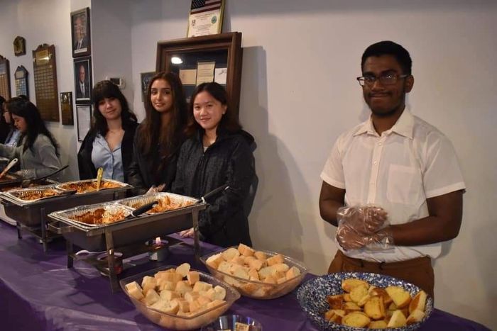a group of people are standing around a table filled with food .