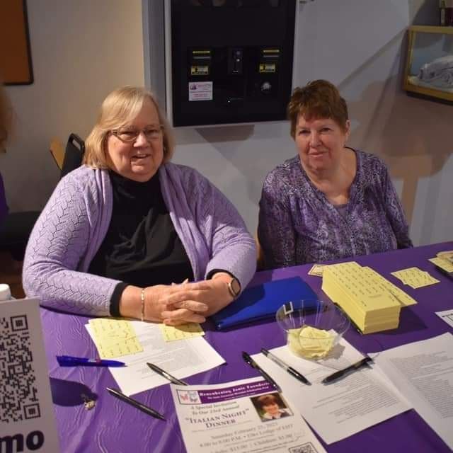 two women sit at a table with a sign that says mo