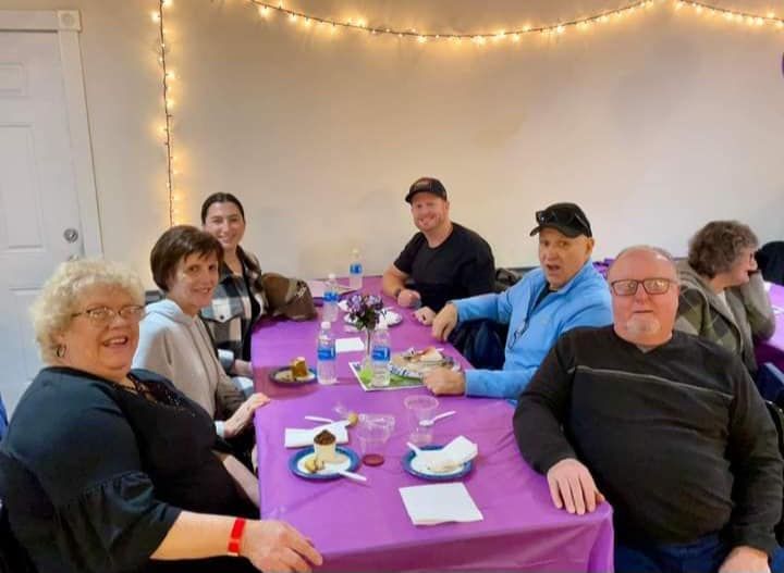 a group of people are sitting at a table with purple tables cloths .