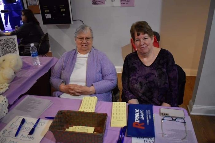two women are sitting at a table with a sign that says public roll .