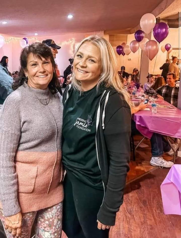 two women are posing for a picture in a room with balloons .