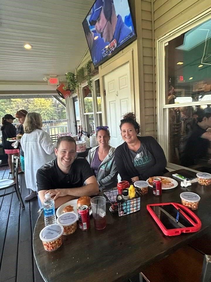 A group of people are sitting at a table in front of a television