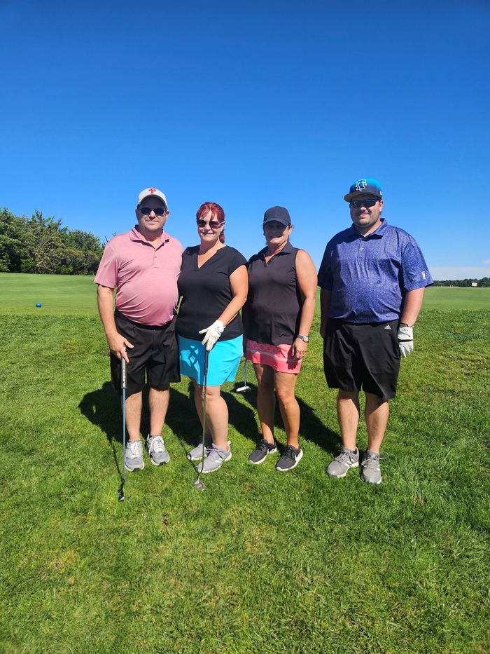 A group of people are posing for a picture on a golf course for the remembering jamie golf tournament