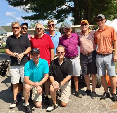 a group of men are posing for a picture in front of a golf cart .