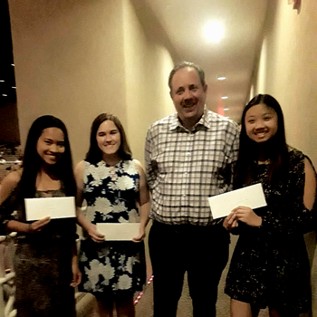 a group of people standing in a hallway holding checks