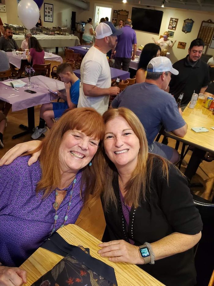 two women are posing for a picture while sitting at a table